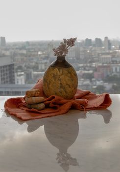 Dried flowers in beautiful ceramic yellow vase handmade on marble table of living room and city view. Home decor. Space for text. Selective focus.