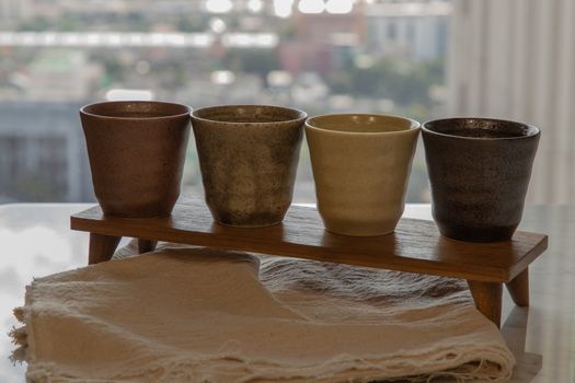 Four ceramics mugs handmade on marble table of living room and city view. Home decor. Space for text. No focus, specifically.