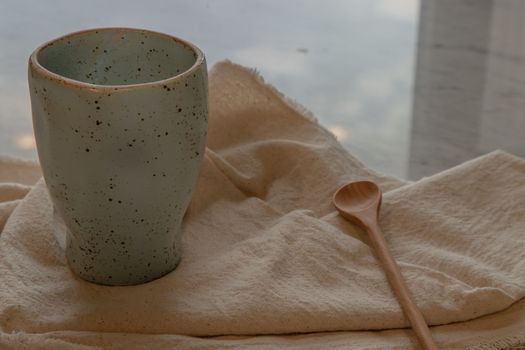 Blue ceramic mug handmade with wooden spoon on marble table of living room and city view. Home decor. Space for text.