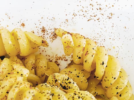 close-up view of cooked fusilli pasta seasoned with spices, paprika and pepper. Italian cuisine.