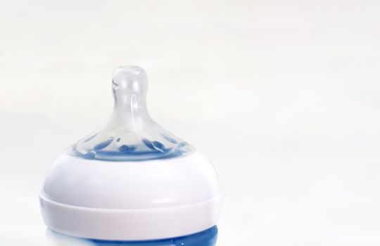 the transparent silicone teat of a blue baby bottle isolated on a white background.