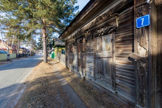 An old one-story wooden house with carved shutters in the Russian style.