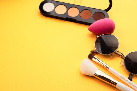 Eyeshadows on a yellow background professional cosmetics makeup brushes soft sponge fashion glasses. High quality photo