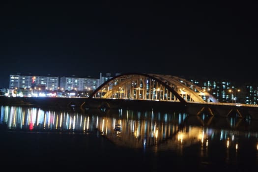 Night view of a beautiful scene of bridge over sea water in the evening time with colorful lights.