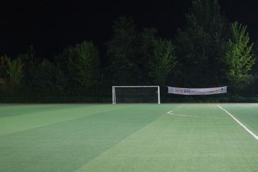 Night view of a soccer goal net under flood lights. Closeup view of goal net in a soccer playground