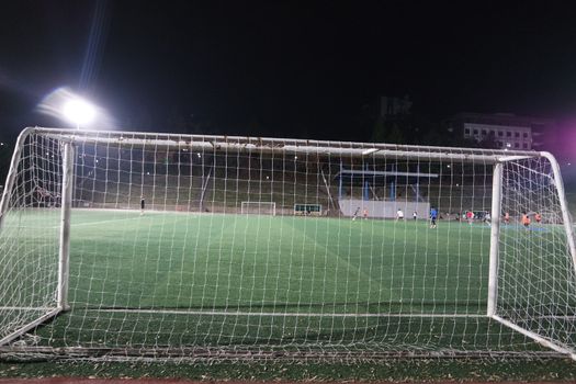 Night view of a soccer goal net under flood lights. Closeup view of goal net in a soccer playground