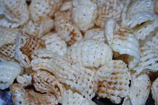 Closeup view of freshly fried chips as fast food for tea break. Potato chips with spices sprinkled on it. Fast food background for advertisements.