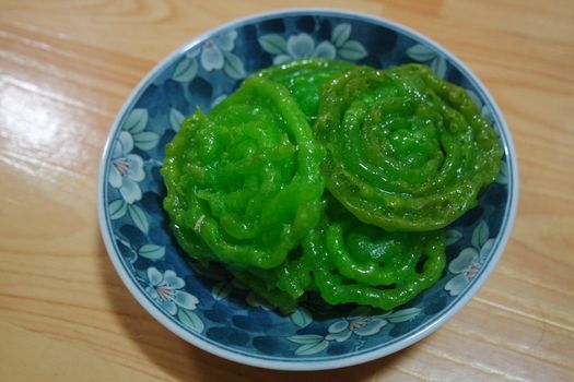 Crispy sweet Asian dessert green Jalebi cooked and served in ceramic plate, Indian sweet street food with juicy syrup, a closeup view.