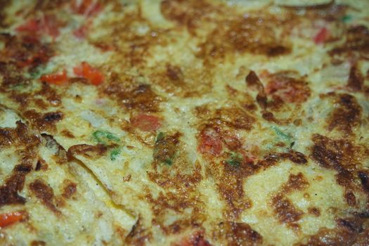 Close-up view with selective focus of egg omelet with peppers and spices sprinkled