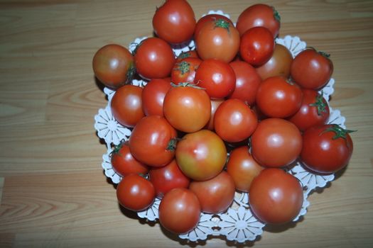 Close-up view of red tomatoes in white basket on a wooden floor in market for sale. A fruit background for text and advertisements
