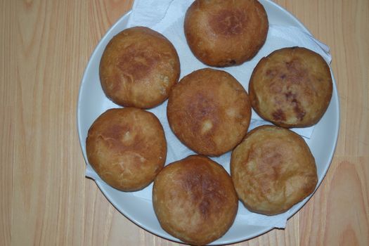 Closeup view of homemade tasty potato bread rolls bun placed in a white plate over a wooden floor.