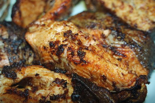 Spicy and crunchy barbecue of fried fish fillet on a white background. Homemade grilled trout fish steaks for health nourishments.