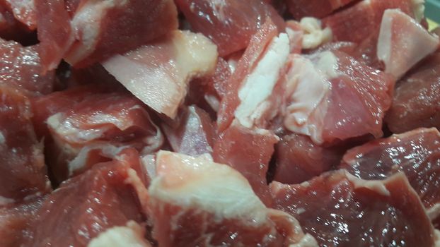 Close up view of fresh finely chopped meat cubes. Red meat small steaks with whitish meat fat.