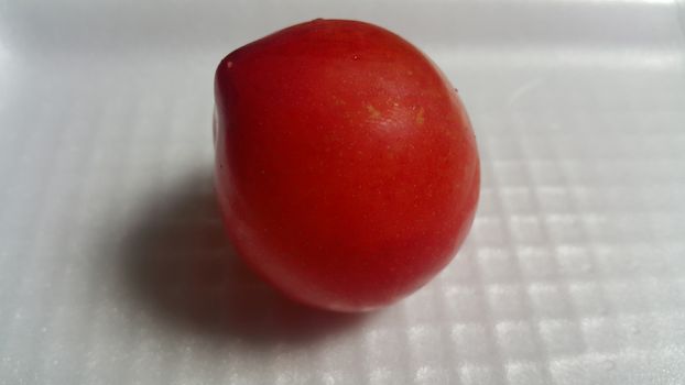 Closeup view of red plum on a white grey background. Freshly harvested plum making heart shape appearance in the view from angle.