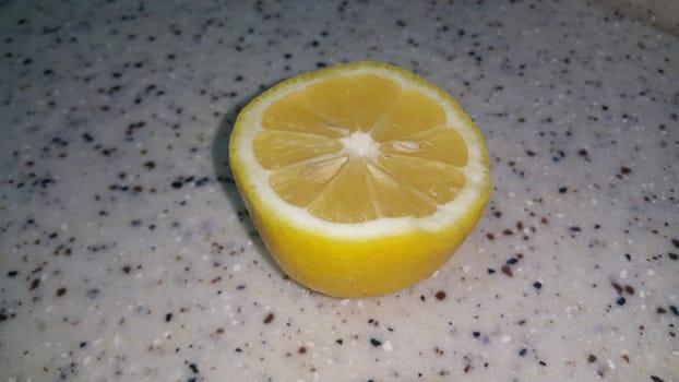 Fresh lemon slices with yellow peelings placed on a grey floor. Top view of fresh juicy lemon slice background