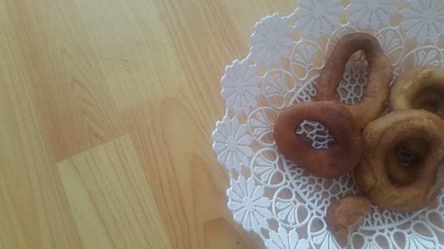 Closeup view of a set of freshly prepared donuts served on white changair. Donuts are placed in a changair over wooden floor