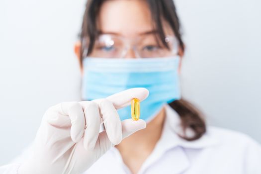 Close up Scientist hands putting in nitrile latex gloves holding Omega 3 capsule in labcoat wearing nitrile gloves, doing experiments in lab