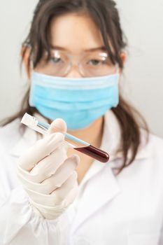 Technician scientist analyzing holding blood sample in test tube in laboratory for testing it on COVID, COVID-19, coronavirus virus analysis