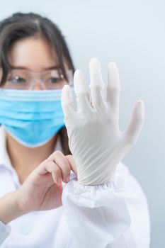Close up Scientist hands putting in nitrile gloves in labcoat wearing nitrile gloves, doing experiments in lab