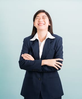 Teenage girl long hair is standing with her arms crossed wearing suit and white shirt on blue background