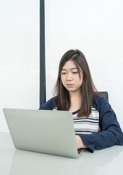 Young female student sitting in living room using laptop at desk learning online