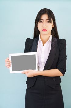 Young women in suit holding her digital tablet standing against blue background