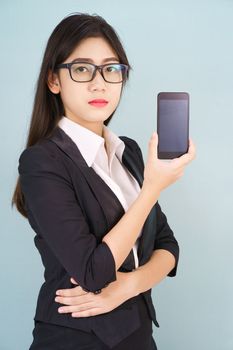 Young women in suit holding her smartphone standing against blue background