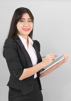 Young women in suit using her digital tablet standing against gray background
