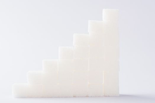 Ascending stacks of sugar cubes graph chart, studio shot isolated on white background, health high blood risk of diabetes concept