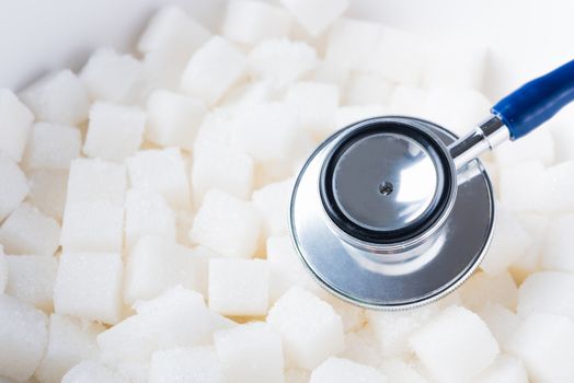 Sugar cube sweet food ingredient texture background and doctor stethoscope, studio shot health high blood risk of diabetes and calorie intake concept