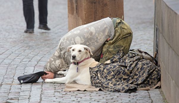 Beggar with dog begging for alms on the street in Prague, Czech Republic