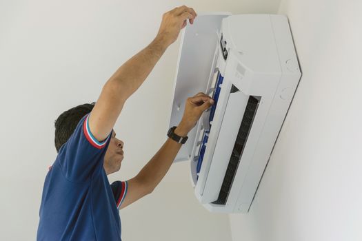 Air conditioner repairers in blue uniform are checking and repair air hanging on the wall.