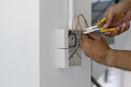 Technicians are using pliers to cut wires to install plugs and switches on the front door.