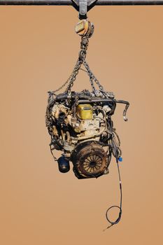 The old engine of the car hung on the hoist isolated on pastel color background, with clipping path.