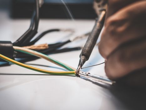 Electricians are using a soldering iron to connect the wires to the metal pin with soldering lead.