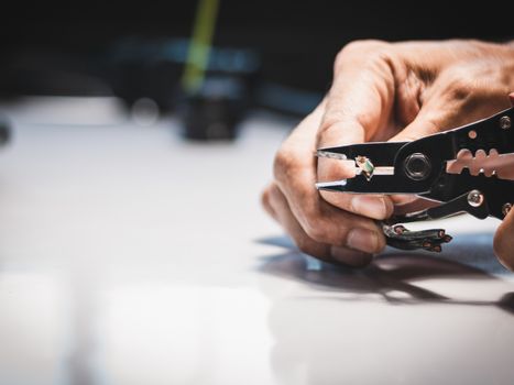 Closeup at the hand of an electrician is using electrical stripping pliers in industrial applications.