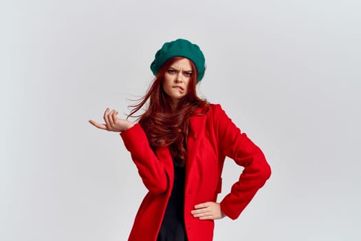 Portrait of a woman in a red coat and in a green hat dark clothes light background model cropped view. High quality photo