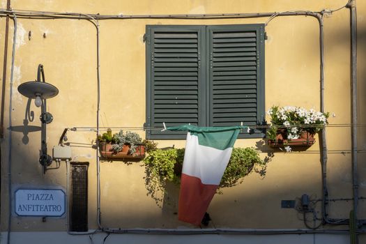 Italian Window with Wooden Shutters in a plastered wall. Decorated With Fresh Flowers