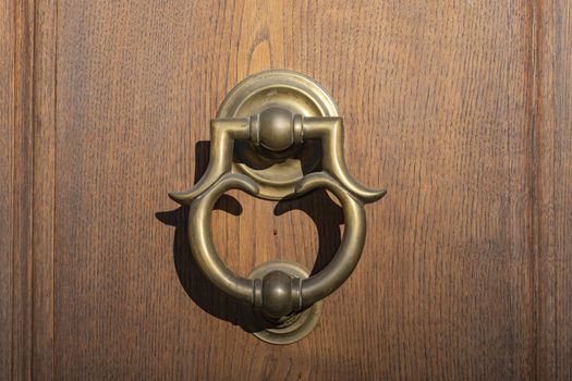 Antique door knocker on wooden door. Vintage, retro background