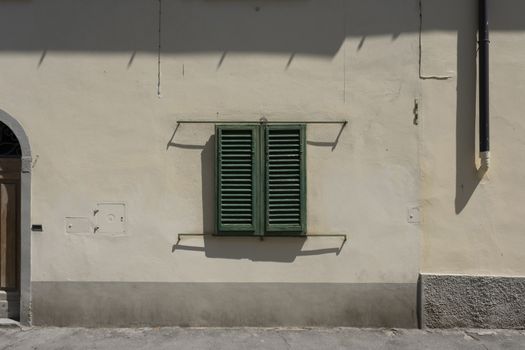 Italian Window with Wooden Shutters in a brick wall. Decorated With Fresh Flowers