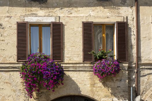 Italian Window with Wooden Shutters in a brick wall. Decorated With Fresh Flowers