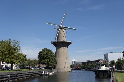 Tall wind mill near water canal and alley in Schiedam, the Netherlands