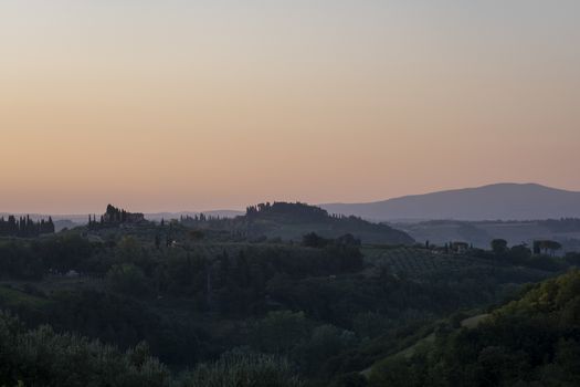 Tuscany, rural landscape in Crete Senesi land. Rolling hills, countryside farm, cypresses trees, green field on warm sunset. Siena, Italy, Europe