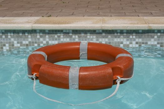 Red life buoy floating in swimming pool.