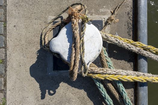 Thick ropes wrapped around a mooring post in the port of rotterdam.