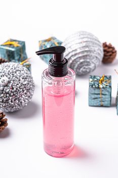 Face washing pink gel for face makeup clean, liquid soap in plastic dispenser bottle near to Christmas New Year ornaments and toys, beauty body care concept, holidays shopping