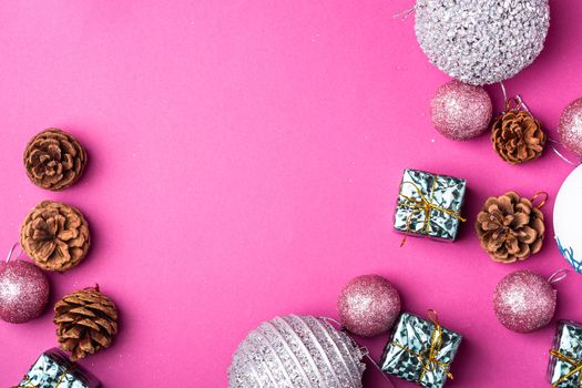 Christmas New Year composition. Gifts, fir tree cones, silver ball decorations on pink background. Winter holidays concept. Flat lay, top view, copy space