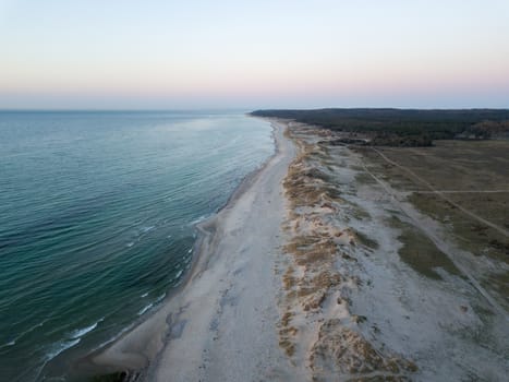 Melby, Denmark - April 18, 2019: Aerial drone view of the coastline beach, sand dunes and forest during sunset.