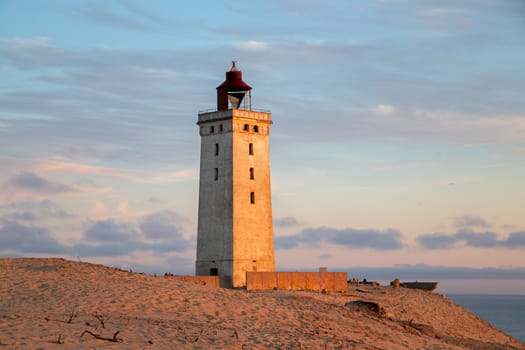 Lokken, Denmark - July 15, 2019: Rubjerg Knude Lighthouse and sand dunes during sunset time.