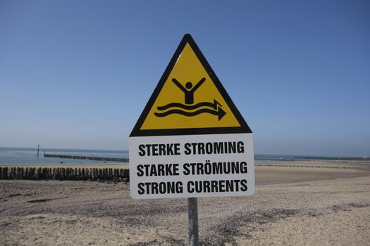 Strong current sign on beach with blue sea in the background in the Netherlands